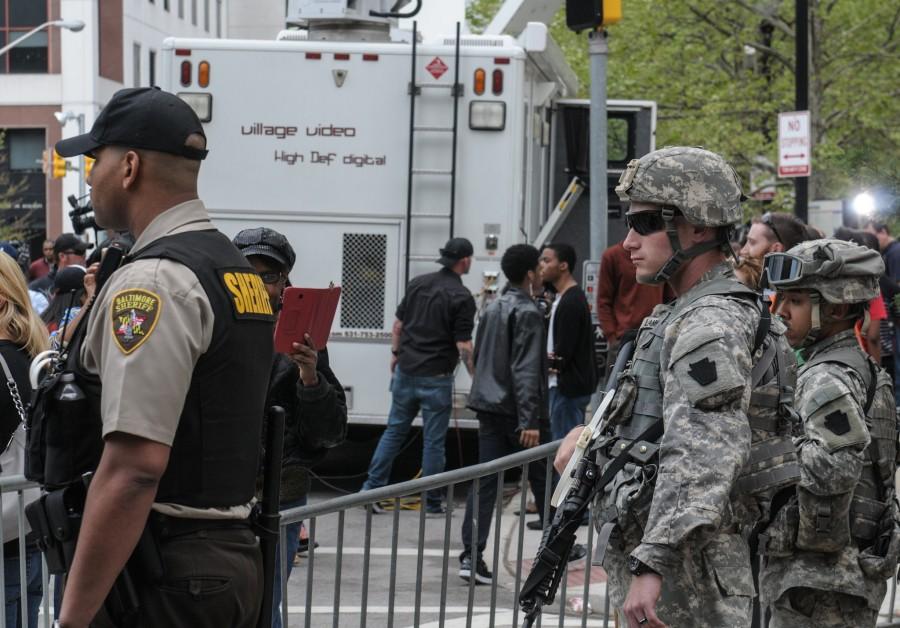 Maryland Army National Guard Soldiers and local law enforcement watch protesters march past City Hall, Baltimore, April 30, 2015. The marchers shouted slogans calling for justice, equality and peace for fellow Baltimore residents. 