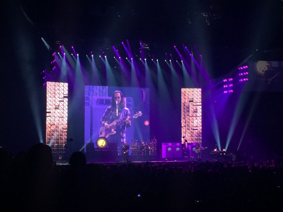 Rush play Roll the Bones during their concert at U.S. Airways Center in Phoenix on Monday night. From left to right: Alex Lifeson (guitar), Neil Peart (drums) and Geddy Lee (bass and vocal). Lee is pictured on the big screen.