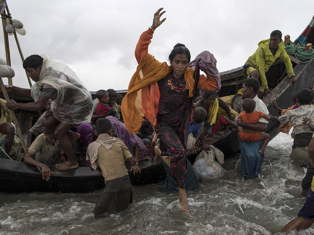 Rohingya refugees jump from a wooden boat as it begins to tip over after travelling from Myanmar, on Sept. 12, in Dakhinpara, Bangladesh. 