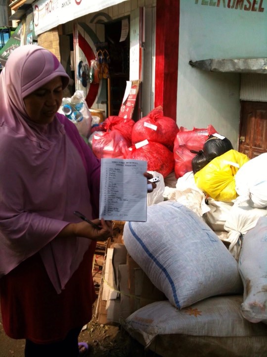 Women keeping record of the trash deposited by people in Indonesia.