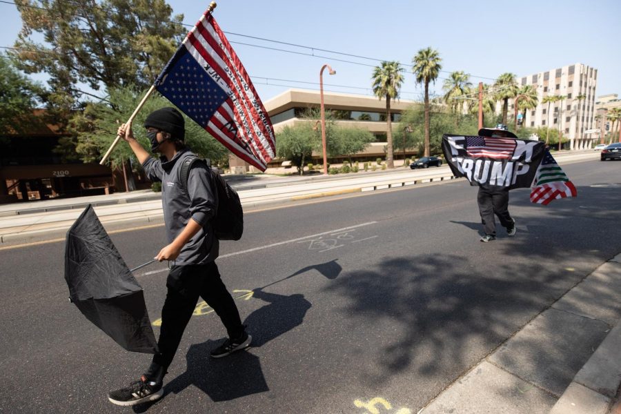 Protesters walk down Central Ave into oncoming traffic with an upside-down American flag, the universal symbol for distress or great danger.
