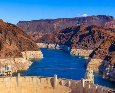 Hoover Dam holds back Lake Mead, where exposed pale rock shows how far water levels have fallen along parts of the reservoir.