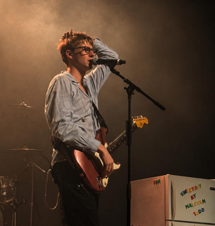 Malcolm Todd performing on stage, holding a guitar.